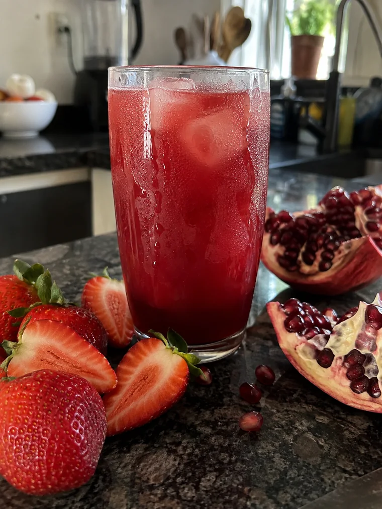 Copo de suco vermelho gelado com morangos e romã